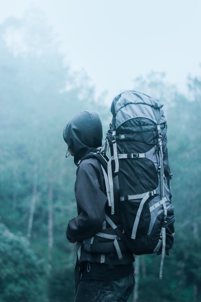 our-story Solo hiker with large backpack in a misty forest, exploring natures serene beauty.